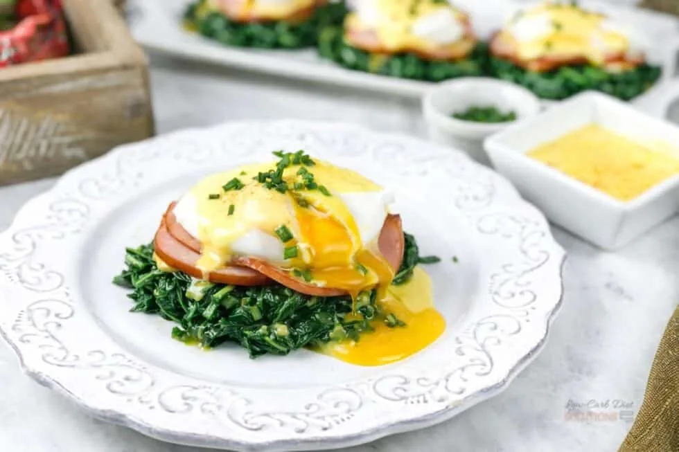 Low-carb eggs Benedict with a poached egg and hollandaise sauce over sautéed spinach and Canadian bacon