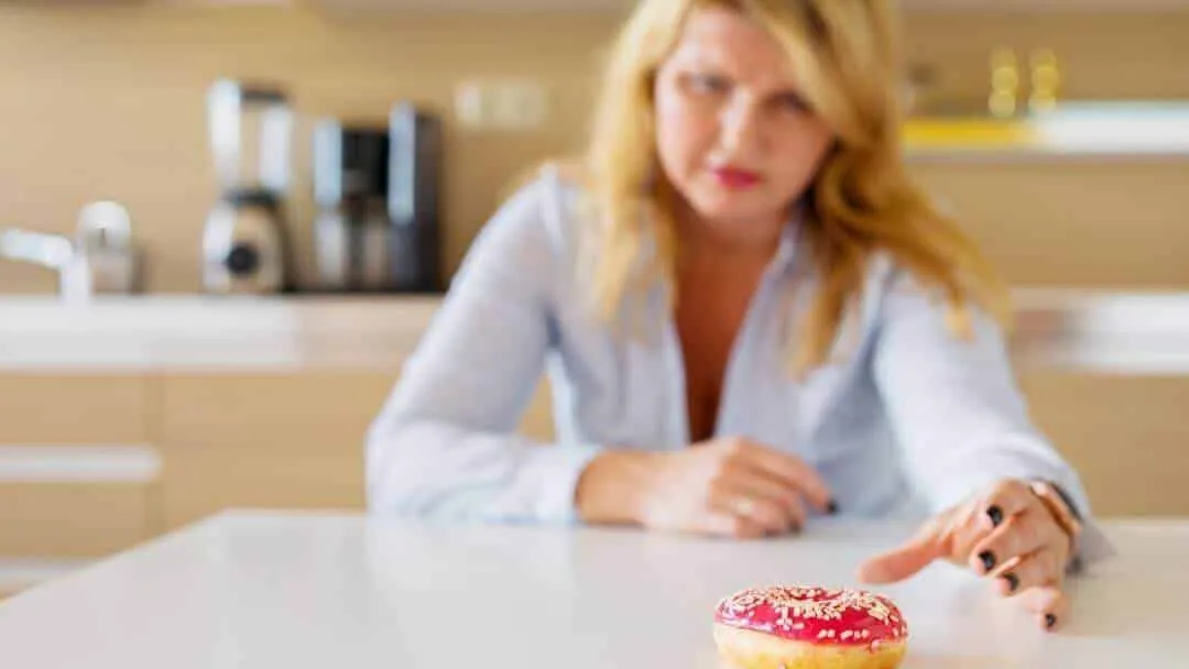 woman reaching for sugary donut during emotional eating moment