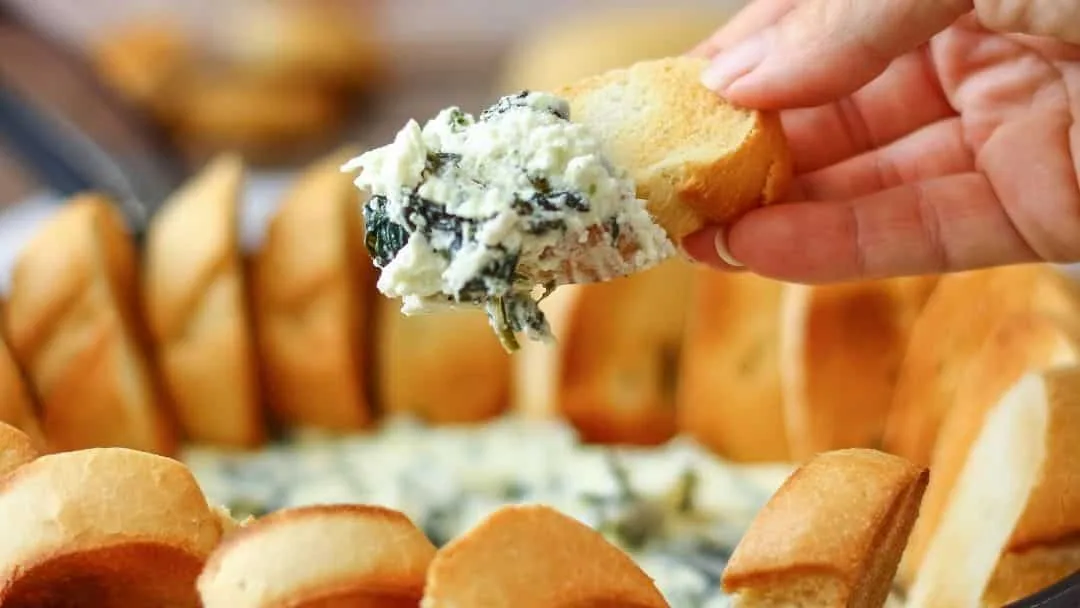 Warm feta, spinach, olive and cream cheese dip in a baking dish, one of the two Christmas party recipes on this page